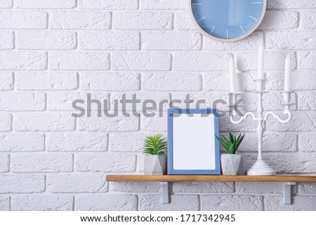 Blue wooden frame with empty photo. Green succulents plants on wooden board. Scandinavian room. Brick white wall background.