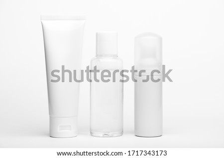Container for cream, shampoo, toiletry. Unbranded plastic tube and flacons. Bottle with dispenser for cosmetics products. Skincare and beauty concept. Mockup style, copy space. Isolated on white Royalty-Free Stock Photo #1717343173