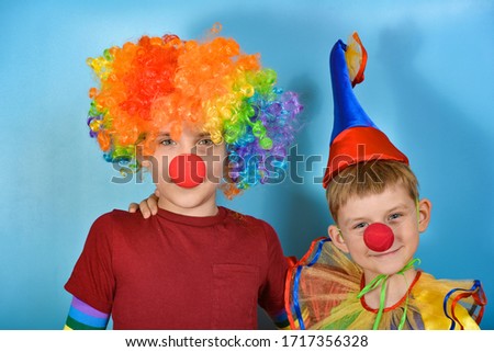 Two cute clowns stand and hug each other.