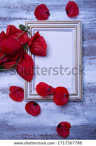 Bouquet of fresh red poppy flowers and empty photoframe on rustic wooden background. Floral composition, event mourning or wedding celebration card. Condolence, commemoration concept. Copy space