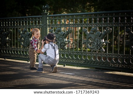 A boy is taking a photo of his little brother on old bridge in Saint-petersburg, Russia