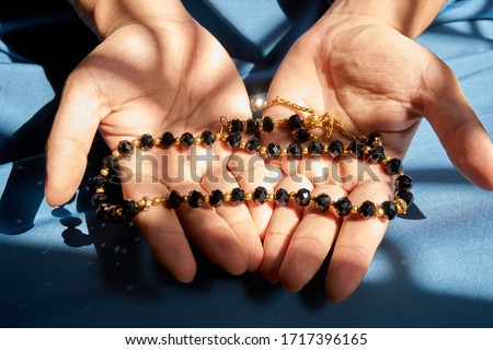   Selective focus of black rosary on palm hand                             