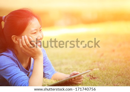 woman college student use tablet pc laying in grass 