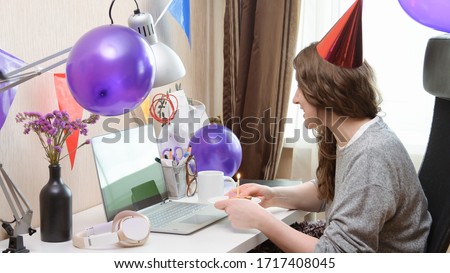 Woman celebrating her birthday through video call virtual party. Lits and blows out candle. Authentic decorated home workplace. Handheld shot with gimbal. Coronavirus outbreak 2020. Royalty-Free Stock Photo #1717408045