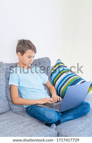 Preteen boy using laptop computer at home. Technology, online learning, distance education, home studying, homework, educational games for kids