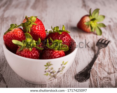 
Delicious red strawberries in a white bowl accompanied by a fork. Horizontal format.