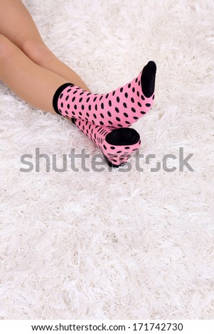 Female legs in colorful socks on white carpet background