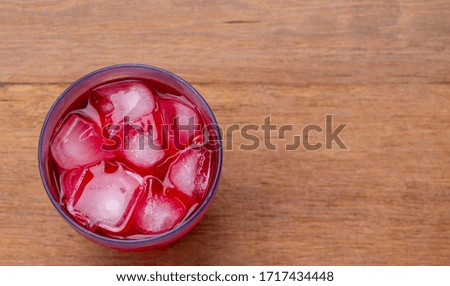 Glass of strawberry juice with ice on a wooden table. Cool and refreshing.
