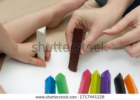 a little boy with his mother are building a multi-colored fence from plasticine bars. family leisure. close-up