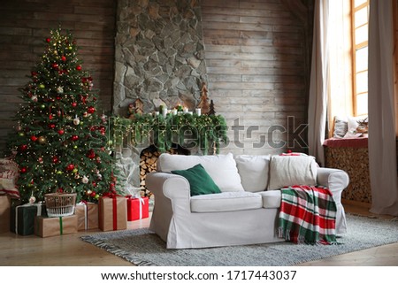 Festive interior with comfortable sofa and decorated Christmas tree