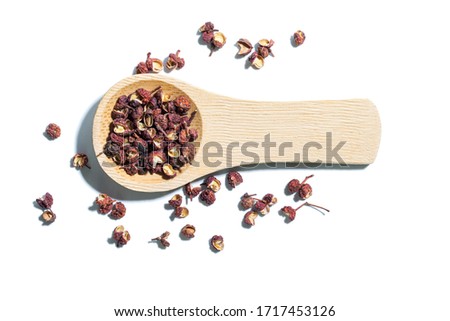 Sichuan pepper or huajiao in wooden spoon isolated on white background, with unique aroma and flavor commonly used in Sichuan  dishes such as Mapo Tofu and hot pot. Macro and close-up.