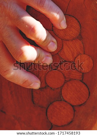 Female hand hold log with circle marks after knots repairing. Red wooden color
