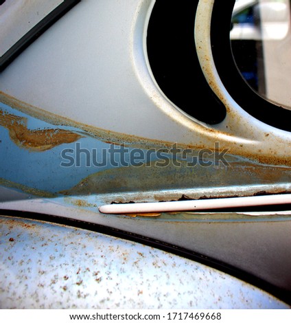 Close up of a side of a rusting old vehicle with part of the back window showing.