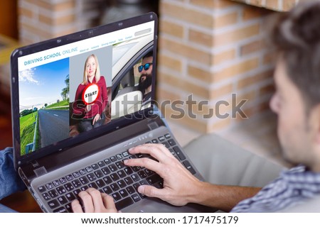 Young man at home using laptop with driving school online website on the screen. Education from home concept. All screen graphics are made up.
