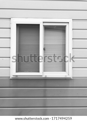 The picture of a window attached to the building's wall. The picture is black and white.