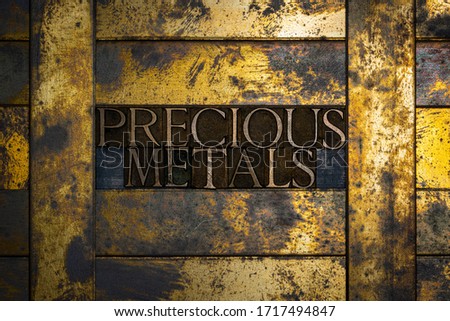 Photo of real authentic typeset letters forming Precious Metals text on vintage textured grunge copper and gold background