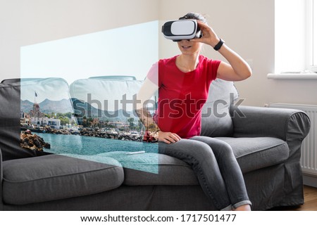Woman with VR glasses sitting on the sofa at home and watching online travel photo. VR booking, getting experiences