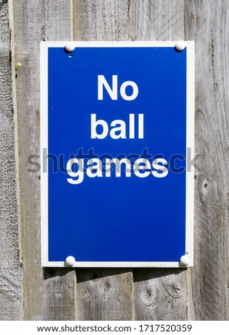 Blue sign prohibiting ball games screwed onto a wooden panel fence background