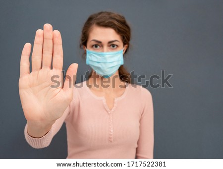 Female woman in medical mask on her face showing sign stop coronavirus with her hands on gray background. People protect their life from viruses and infections. Caucasian girl Stay home, corona virus.