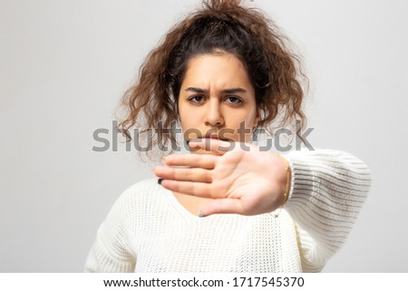 Hold on, Stop gesture showed by young woman hand. Beautiful young woman portrait. Indoor portrait of beautiful brunette young woman with shaggy hairstyle