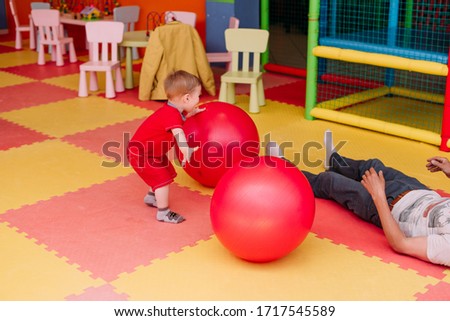 Happy laughing boy 1-2 years old having fun in ball pit on birthday party in kids amusement park and indoor play center.  in playground ball pool. Activity toys for little kid.