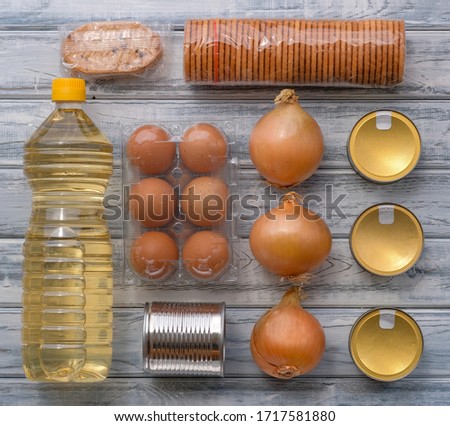 Top view on grocery flat lay with canned food, eggs, vegetable oil and cookies. Food supplies, crisis stock of shelf stable food, layout. Quarantine, isolation period. Safe home delivery.