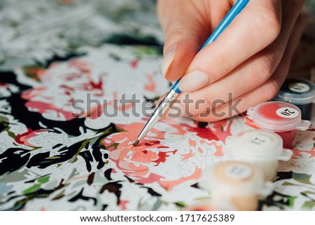 Female hand coloring paint by numbers picture. Creative hobby. Leisure activity at home during self-isolation COVID-19