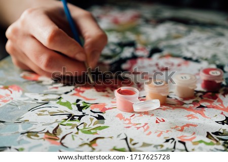 Young girl enjoying painting by numbers picture. Creative hobby. Leisure activity at home during self-isolation COVID-19