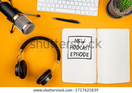 top view of text NEW PODCAST EPISODE on notepad on desk with microphone, computer keyboard and headphones, podcasting concept Royalty-Free Stock Photo #1717625839