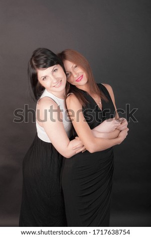 studio portrait of two girlfriends on a black background