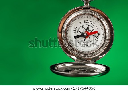 Ancient metal compass on green  background 