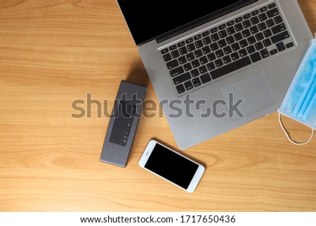 Work from home concept. Top view laptop, smartphone, speaker and face mask on wood table with copyspace for text or design.