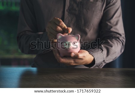 man putting coin to piggy bank, about saving