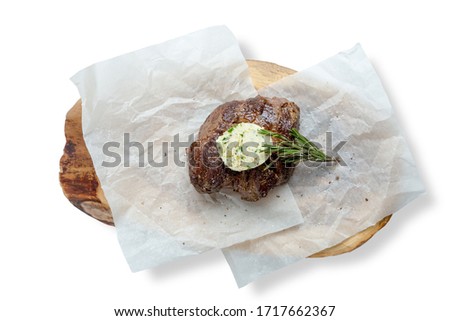 Beef steak minion with aromatic butter and a sprig of rosemary. Served on a wooden board and parchment.