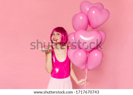 Image of smiling nice woman in wig posing with balloons and cake isolated over pink background