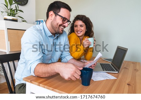 Happy smiling couple calculating their financial investments at home stock photo
