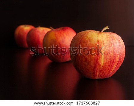 Red apples forming a row in perspective, on a dark background, shallow depth of field