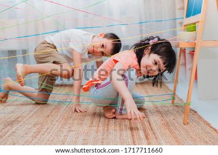 little girl boy brother, siblings, friendschild climbs through a rope web, a game obstacle quest indoors. The concept of active play in the home room, quarantine, self-isolation. Royalty-Free Stock Photo #1717711660