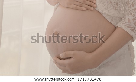 pregnancy, rest, people and expectation concept - happy pregnant woman standing and touching her belly at home