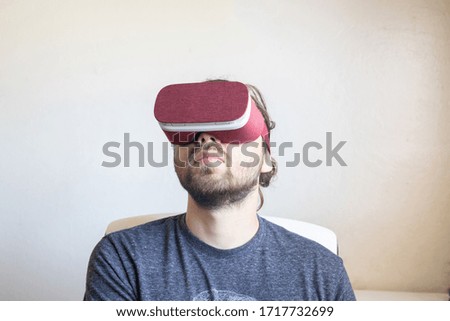 Bearded man wearing  goggles in shelter in place order staying home. Smartphone using with headset. Horizontal, blurred
