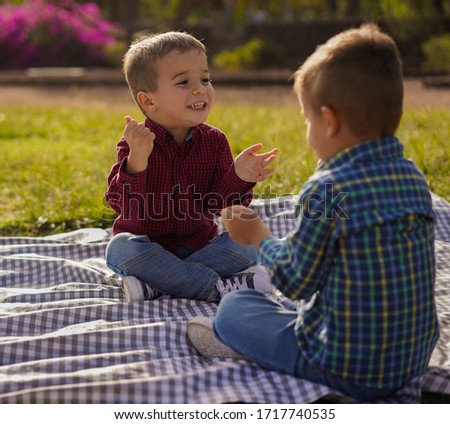 Twin brothers play rock paper scissors together in the park - Brothers having playful time togheter - Family, child, brother love and joyful