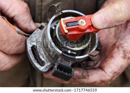 Disassembled car Ignition distributor without cap with Hall transducer and distribution cam in serviceman hands close-up, vehicle ignition system maintenance Royalty-Free Stock Photo #1717746559