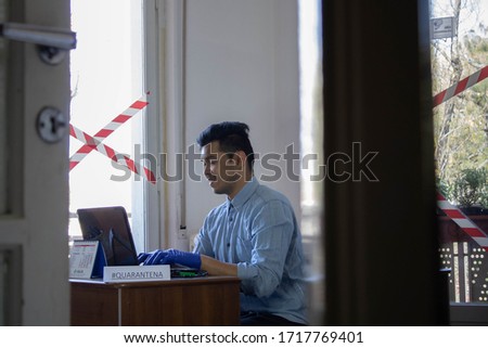 man using computer and also phone wearing gloves 