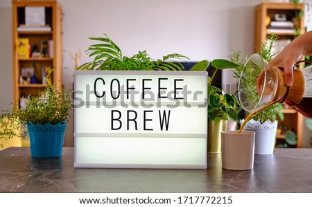 Lightbox written "Coffee Brew". Home environment in the background. Concept for special brew coffee and making coffee at home.