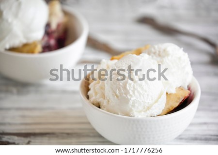 Fresh made homemade cherry cobbler served with two scoops of vanilla ice cream. Selective focus with blurred background.