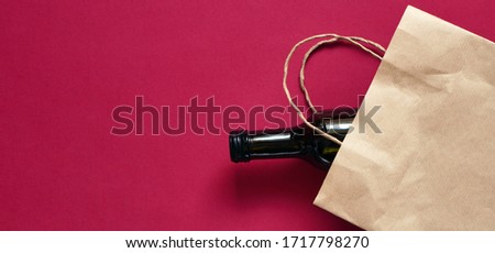Banner paper bag with dark glass bottle of wine, alcohol present. Flat lay on maroon background, zero waste. Garbage recycling Royalty-Free Stock Photo #1717798270