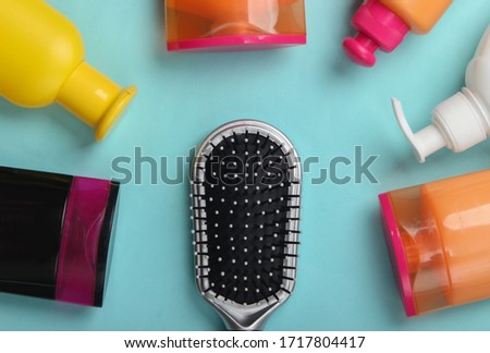 Hair brush with shampoo bottles on blue pastel background. Hair care. Hygiene. Beauty flat lay. Top view