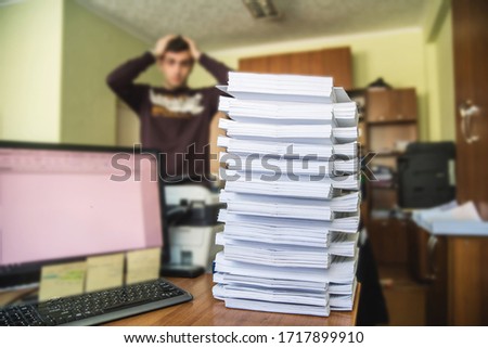 Man and stack of papers in office on the table