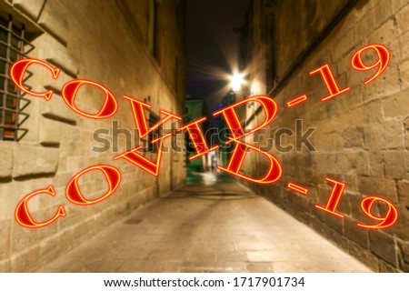 Coronavirus in Barcelona, Spain. Covid-19 sign on a blurred background. Concept of COVID pandemic and travel in Europe. Gothic quarter at night. Empty alleyways