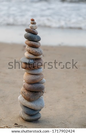 Stones piled in a pyramid on the sand against the background of the ocean. Calm relaxation picture.